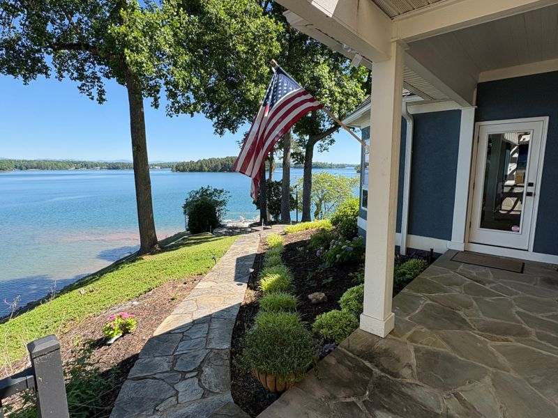 A natural flagstone walkway and layered evergreen plantings beside a lakefront porch